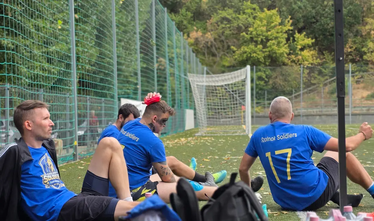 Csapattagok pihennek a pálya szélén két meccs között